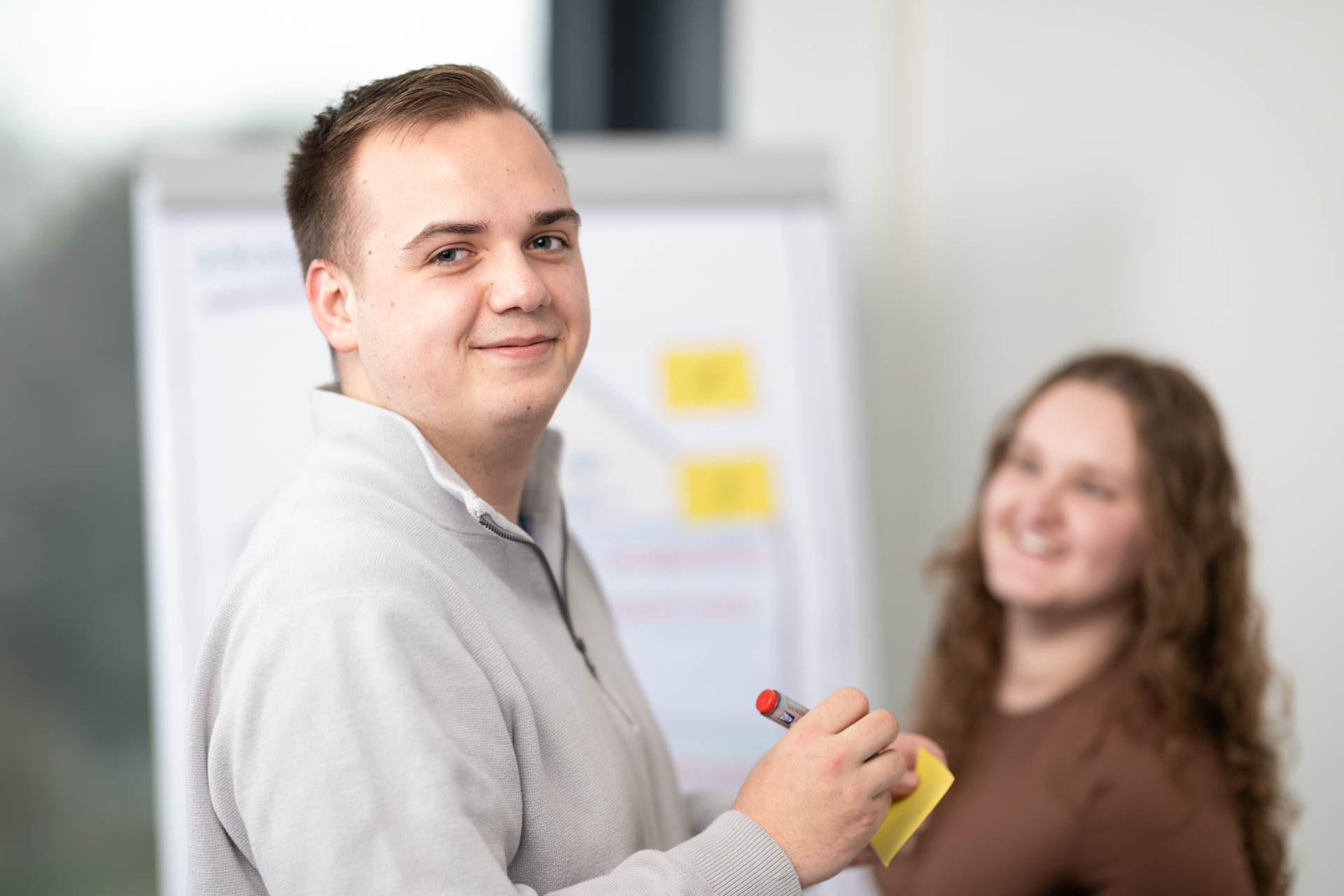 Junger Mann und junge Frau im Austausch vor einem Flipchart am Informationsanlass der IBBM in Burgdorf.